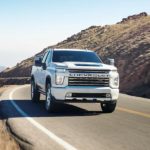 A white 2022 Chevy Silverado 2500HD is shown from the front driving on an open road after winning a 2022 Chevy Silverado 2500HD vs 2022 Ford F-250 comparison.