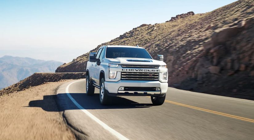 A white 2022 Chevy Silverado 2500HD is shown from the front driving on an open road after winning a 2022 Chevy Silverado 2500HD vs 2022 Ford F-250 comparison.