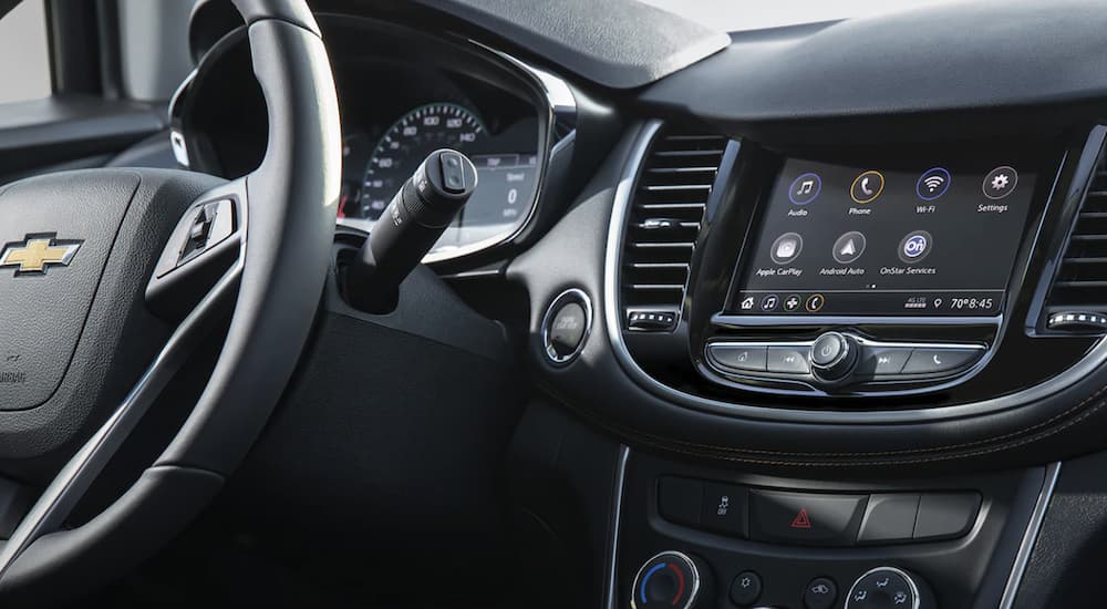 The black interior of a 2022 Chevy Trax shows the steering wheel and infotainment screen.