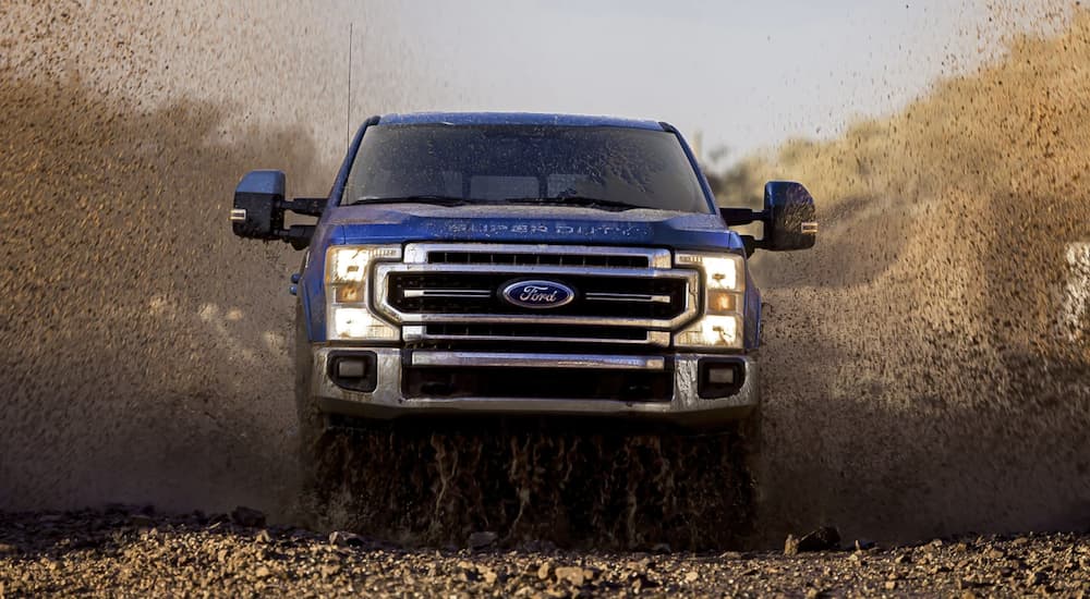 A blue 2022 Ford F-250 HD is shown from the front kicking up dust. 