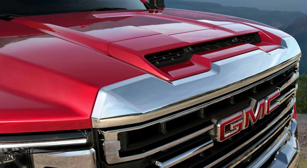 A close up of the grille of a red 2022 GMC Sierra 2500HD SLT from an angle.