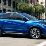A blue Honda HR-V is shown from the side driving on a city street.