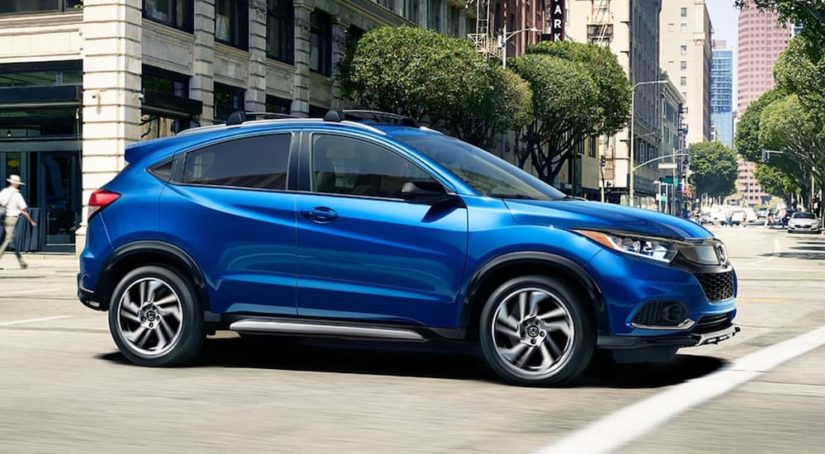 A blue Honda HR-V is shown from the side driving on a city street.