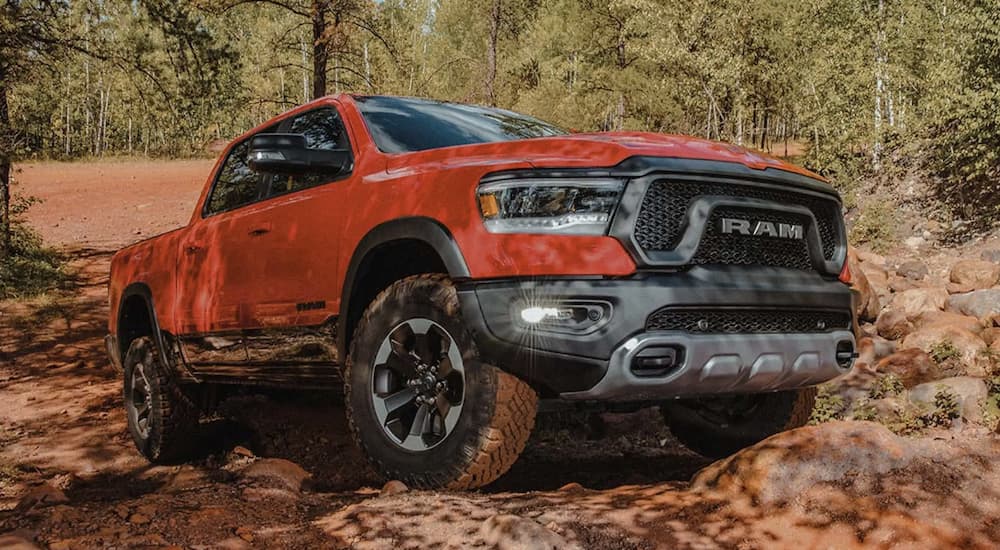 An orange 2022 Ram 1500 is shown from the front parked on a pile of rocks.