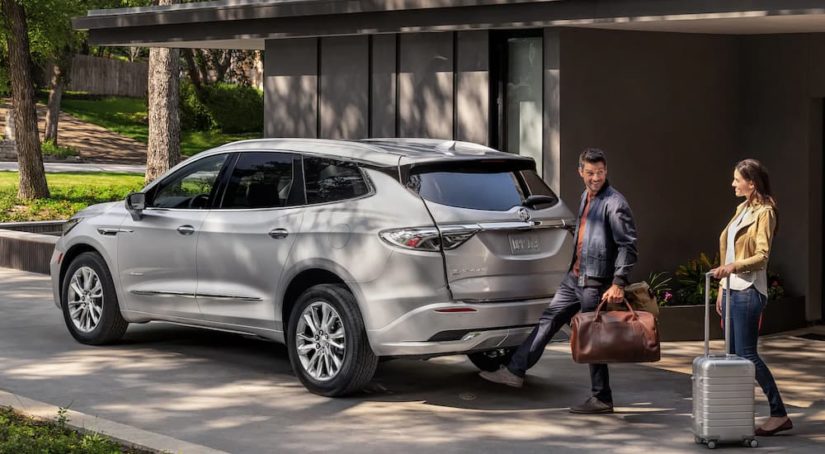 A man is shown opening the rear liftgate of a silver 2022 Buick Enclave.