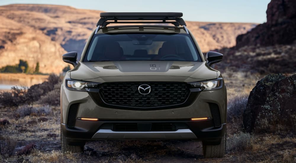A tan 2023 Mazda CX-50 SUV is shown from the front parked in a desert.
