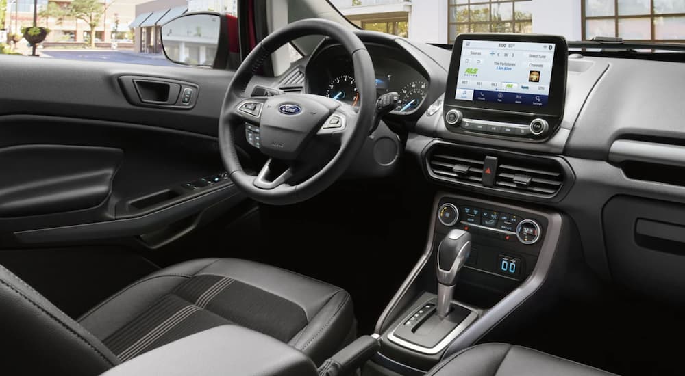 The black interior of a 2021 Ford EcoSport shows the steering wheel and infotainment screen.