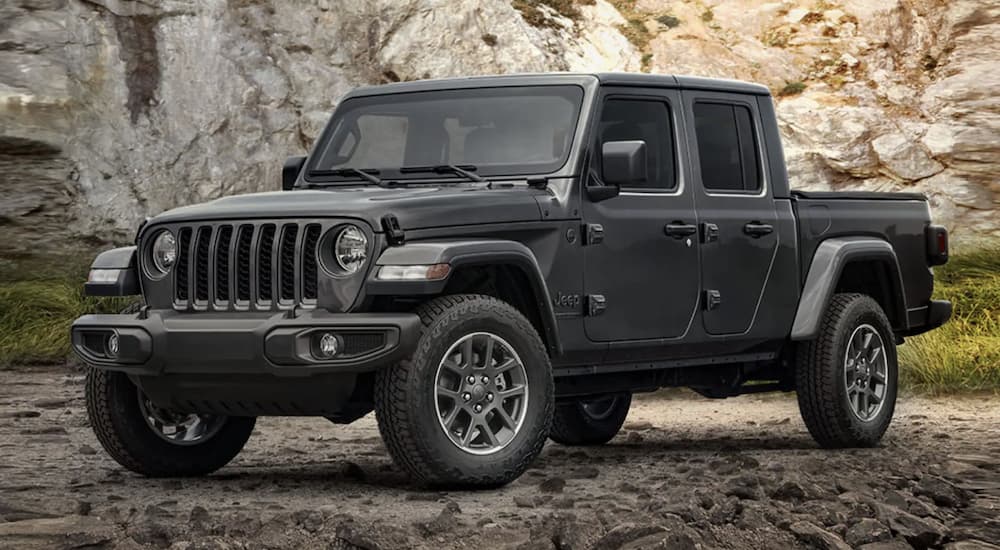 A grey 2021 Jeep Gladiator is shown from the side parked in front of a rocky mountain. 
