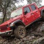 A red 2021 Jeep Gladiator is shown from the side off-roading in the mountains after winning a 2021 Jeep Gladiator vs 2021 Ford Ranger comparison.