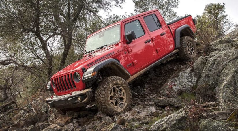 A red 2021 Jeep Gladiator is shown from the side off-roading in the mountains after winning a 2021 Jeep Gladiator vs 2021 Ford Ranger comparison.