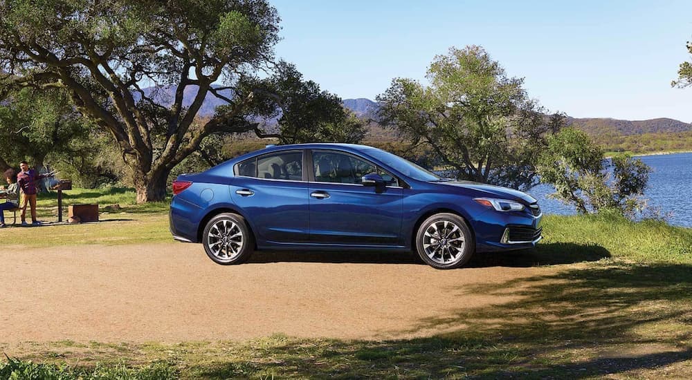A blue 2021 Subaru Impreza Limited is shown from the side parked in a dirt lot.