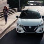 A white 2021 Nissan Sentra is shown from the front driving on a city street after winning a 2021 Nissan Sentra vs 2021 Subaru Impreza comparison.