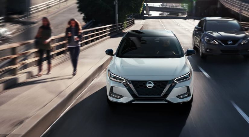 A white 2021 Nissan Sentra is shown from the front driving on a city street after winning a 2021 Nissan Sentra vs 2021 Subaru Impreza comparison.