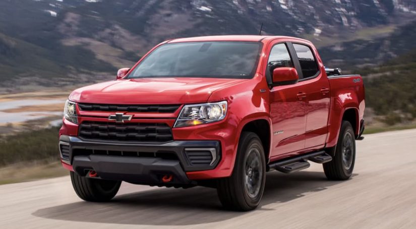 A red 2022 Chevrolet Colorado is shown from the side driving on an open road past a body of water.