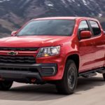 A red 2022 Chevy Colorado Trail Boss is shown from the front driving on an open road.