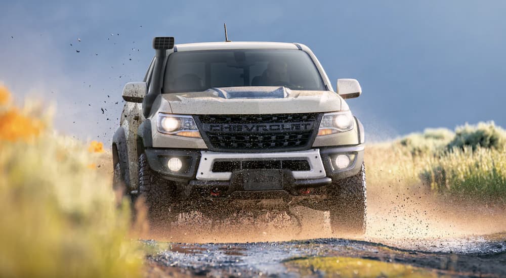 A tan 2022 Chevy Colorado ZR2 is shown from the front off-roading on a dirt path.