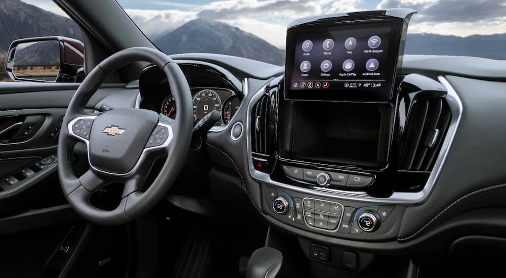 The black interior of a 2022 Chevy Traverse Premier shows the infotainment screen and dash storage.