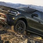 A green 2022 Expedition is shown from the side off-roading on a grassy hill after winning a 2022 Ford Expedition vs 2021 Ford Expedition comparison.