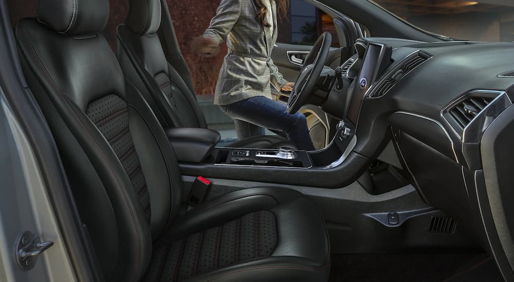 The black and silver accented interior of a 2022 Ford Edge ST shows the steering wheel and center console.