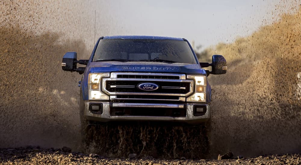 A blue 2022 Ford F-350 is shown driving through a field.