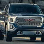 A black 2022 GMC Sierra 1500 Denali is shown from the front driving on an open road after winning a 2022 GMC Sierra 1500 vs 2022 Chevy Silverado 1500 comparison.