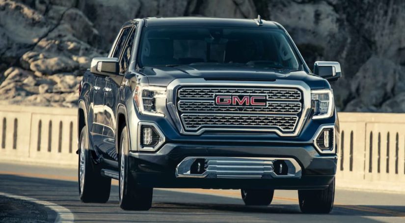 A black 2022 GMC Sierra 1500 Denali is shown from the front driving on an open road after winning a 2022 GMC Sierra 1500 vs 2022 Chevy Silverado 1500 comparison.