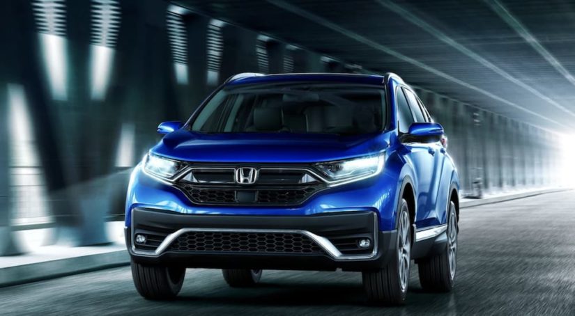 A blue 2022 Honda CR-V Hybrid Touring is shown from the front driving through a tunnel.