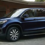 A blue 2022 Honda Pilot EX-L is shown from the side parked in front of a modern house.