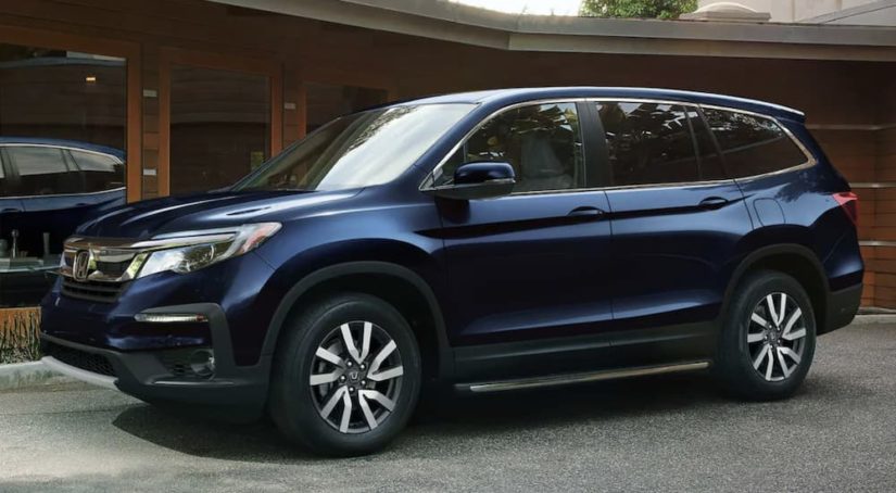 A blue 2022 Honda Pilot EX-L is shown from the side parked in front of a modern house.