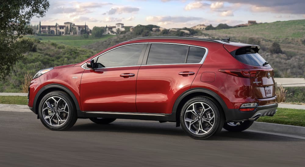 A red 2022 Kia Sportage is shown from the side driving on an open road after leaving a Kia Sportage dealer.