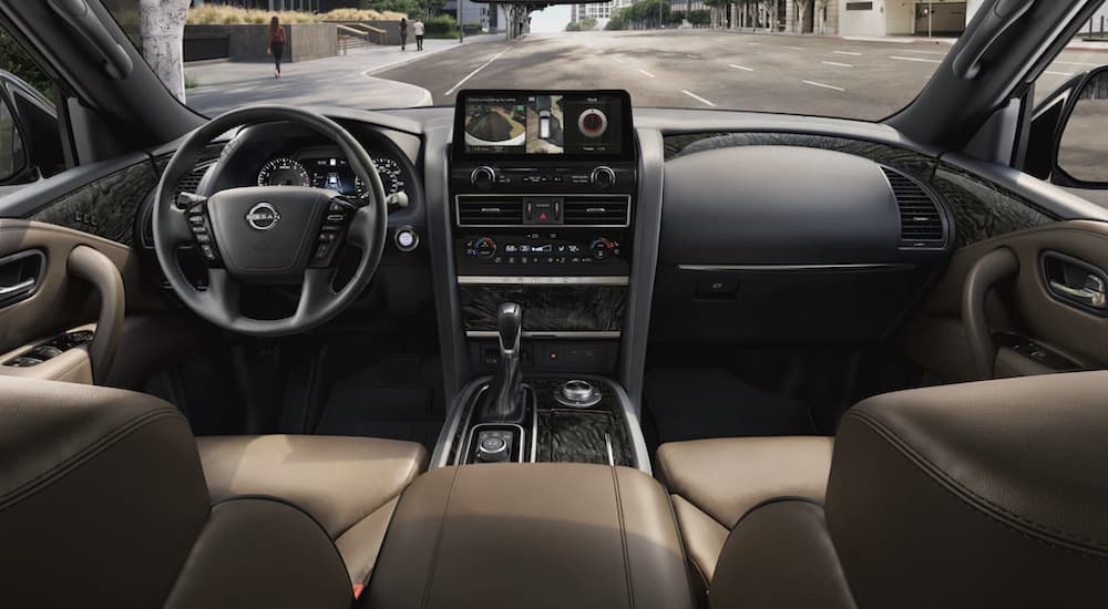 The black and tan interior of a 2022 Nissan Armada shows the steering wheel and infotainment screen.