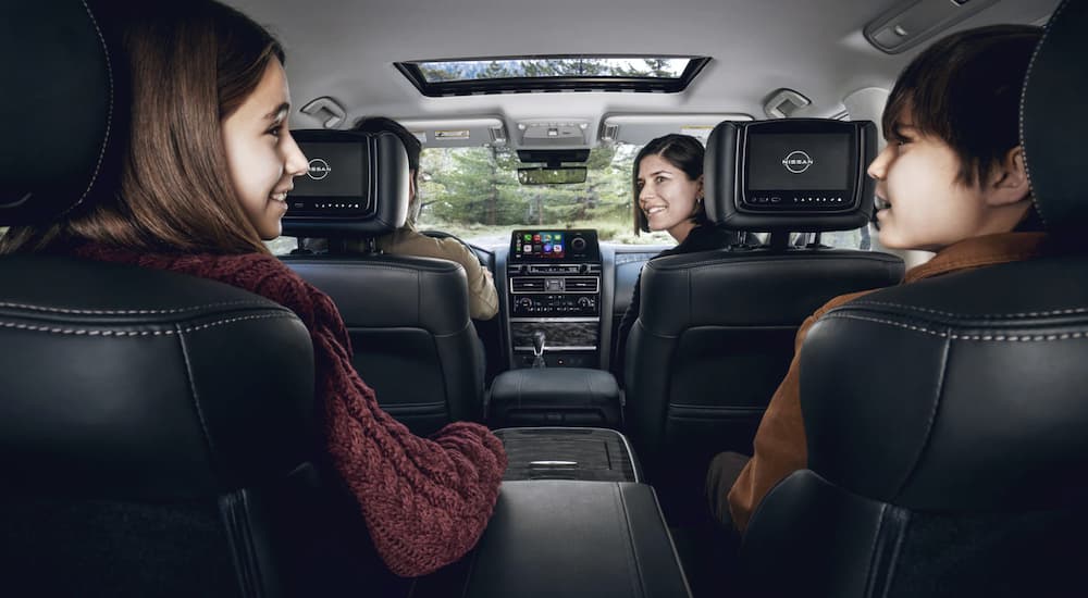 The black interior of a 2022 Nissan Armada shows a family in two rows of seats.