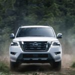 A white 2022 Nissan Armada is shown from the front driving through a forest.
