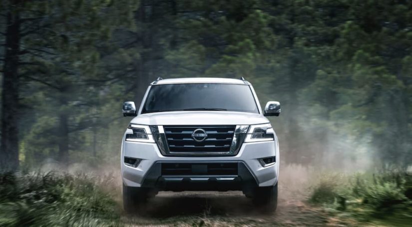 A white 2022 Nissan Armada is shown from the front driving through a forest.