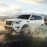 A 2022 Nissan Armada is shown from the side driving through a stream.