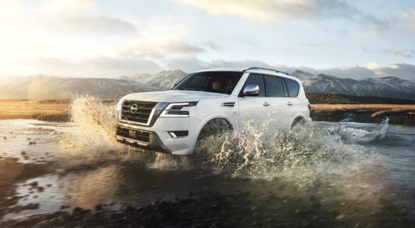 A 2022 Nissan Armada is shown from the side driving through a stream.