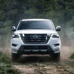 A white 2022 Nissan Armada is shown from the front driving through the forest.
