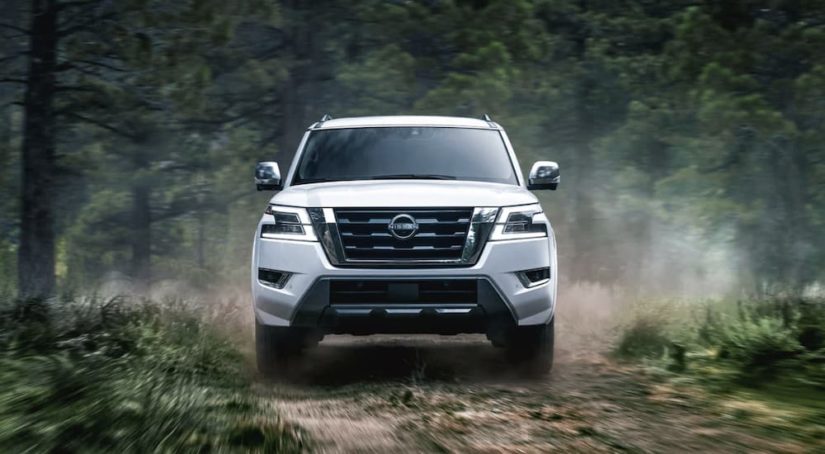 A white 2022 Nissan Armada is shown from the front driving through the forest.