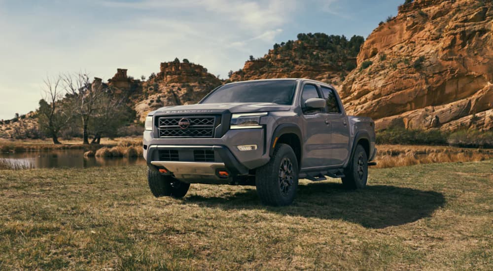 A grey 2022 Nissan Frontier is shown from the front parked in a field after winning a 2022 Nissan Frontier vs 2022 Toyota Tacoma comparison.