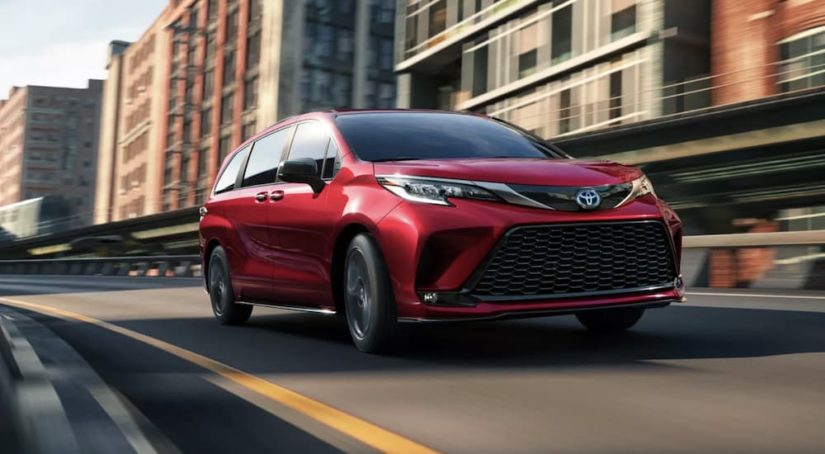 A red 2022 Toyota Sienna XSE is shown from the front driving through a city.