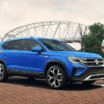 A blue 2022 Volkswagen Taos is shown from the side parked in front of a bridge after winning a 2022 Volkswagen Taos vs 2022 Jeep Compass comparison.