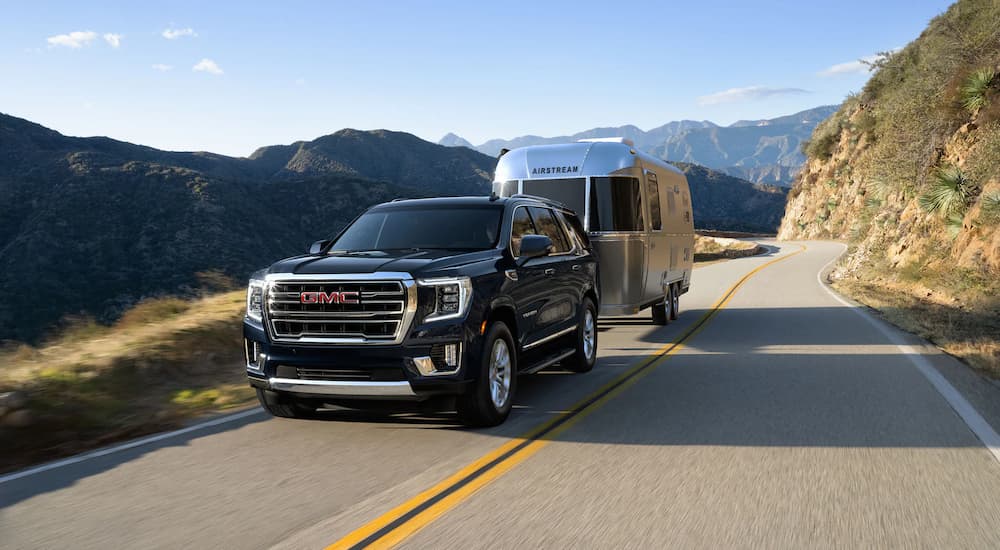 A black 2022 GMC Yukon is shown towing a silver camper.