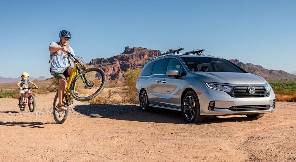 A silver 2021 Honda Odyssey Elite is shown parked in a desert area.