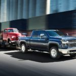 A blue 2022 Chevy Silverado 2500HD is shown towing a red truck.