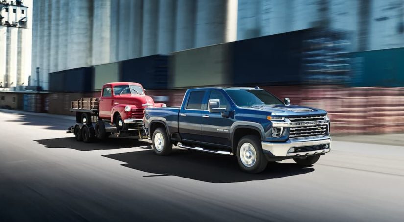 A blue 2022 Chevy Silverado 2500HD is shown towing a red truck.