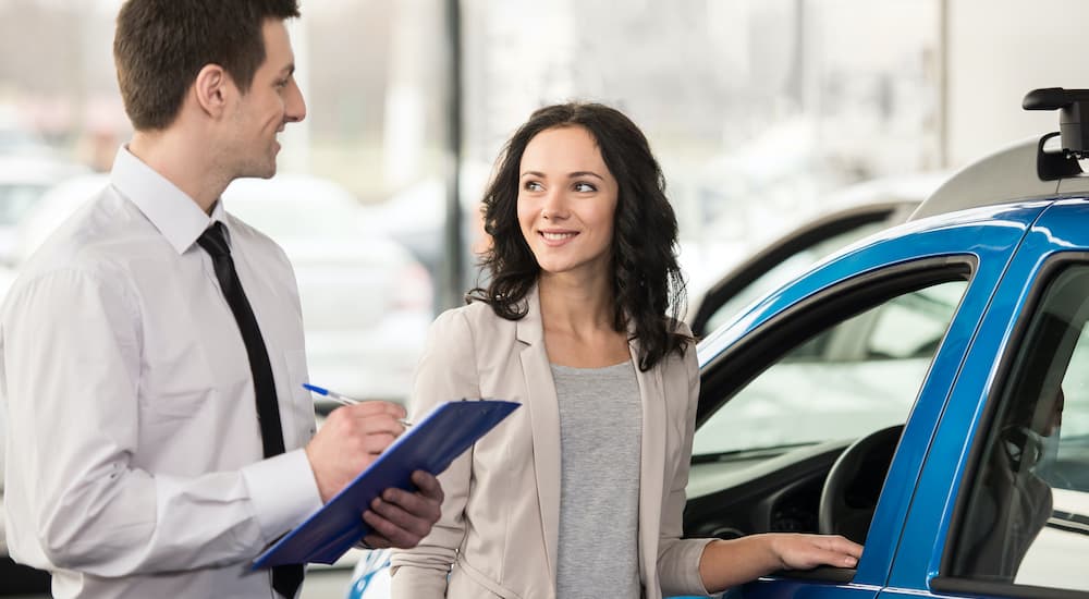 A salesperson is showing a woman a vehicle.