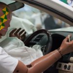 An automotive crash test dummy is strapped into car seat during a practice crash.