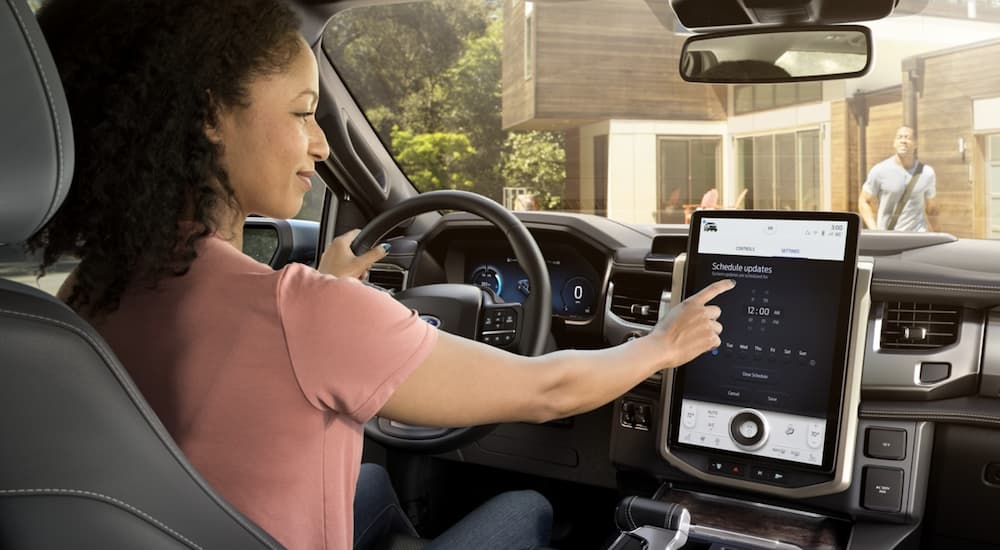 The interior of a 2022 Ford F-150 shows a person operating the infotainment screen.