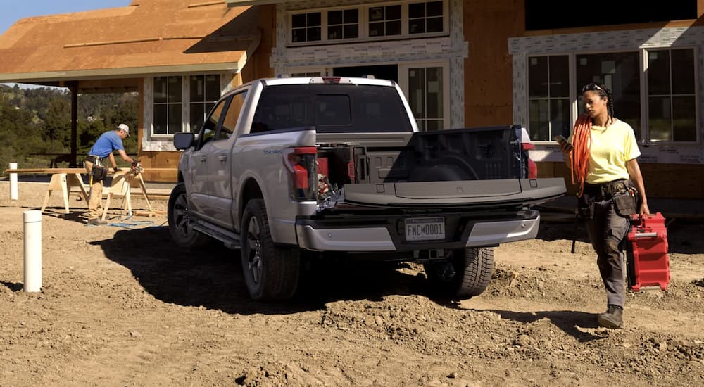 A white 2022 Ford F-150 Lightning is shown from the rear parked at a construction site.