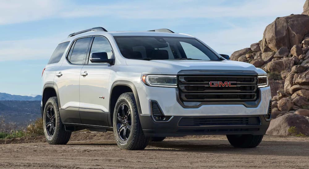 A white 2022 GMC Acadia AT4 is shown from the front parked in the mountains.